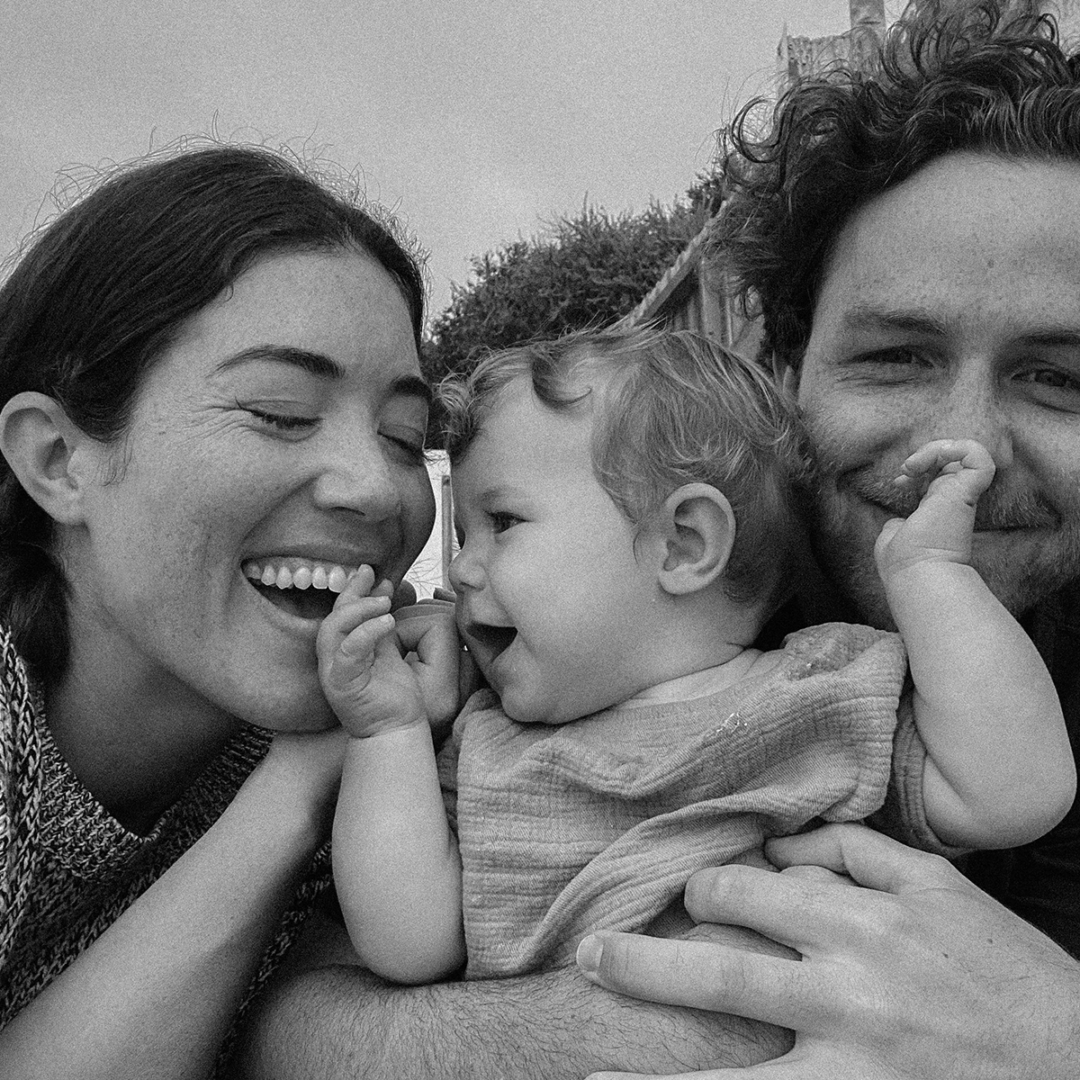 Family portrait of couple laughing and holding up baby