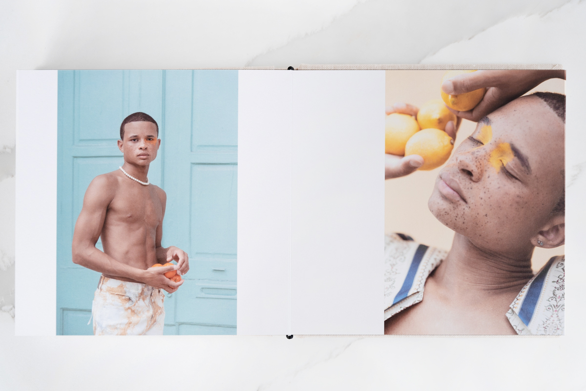 Artifact Uprising Layflat Photo Portfolio Book opened to high-fashion portraits of young man holding citrus