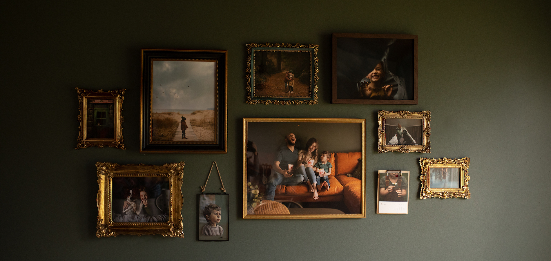 Gallery wall on dark olive green wall filled with family photos in gold and brass frames and an Artifact Uprising Gallery Frame in Walnut