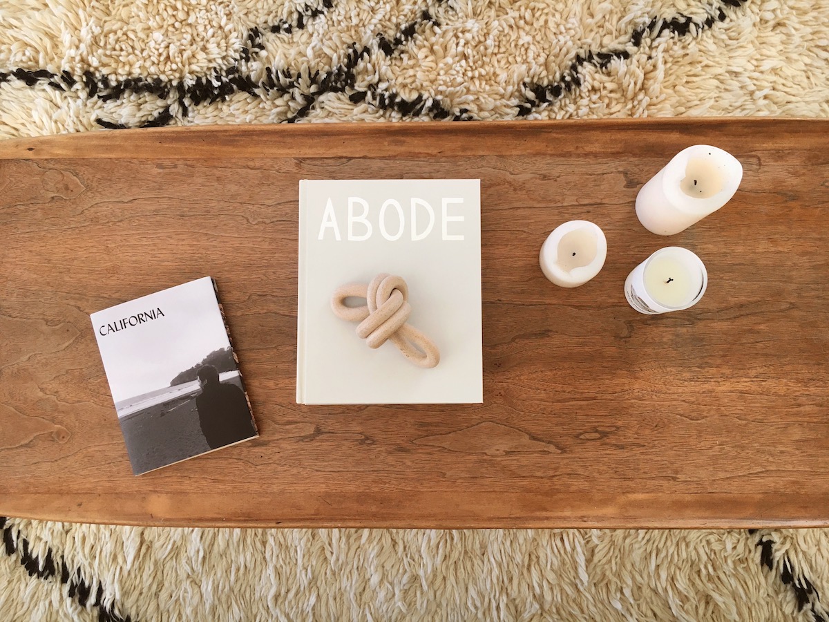 Artifact Uprising Photo-Wrapped Hardcover Book titled Abode on coffee table next to candles and another book titled California