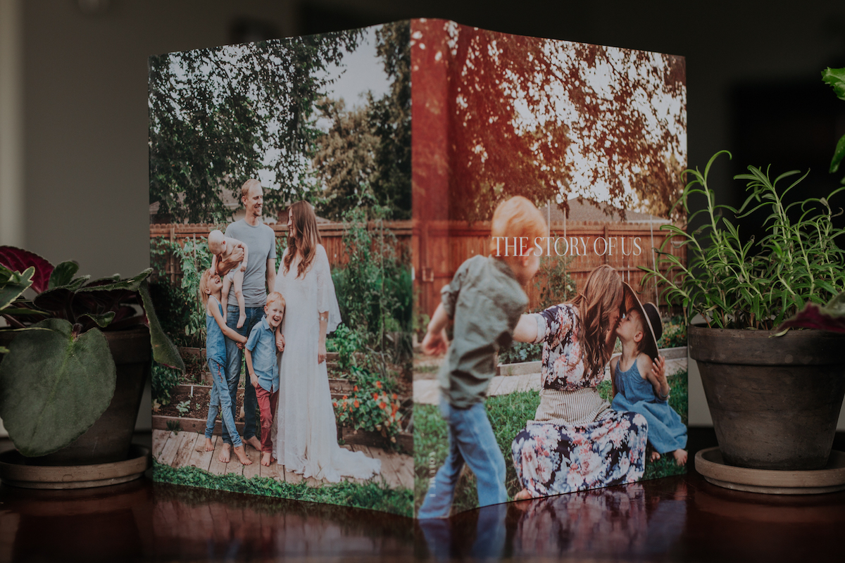 Artifact Uprising Hardcover Photo Book standing open on coffee table with family photos on the cover and back cover visible