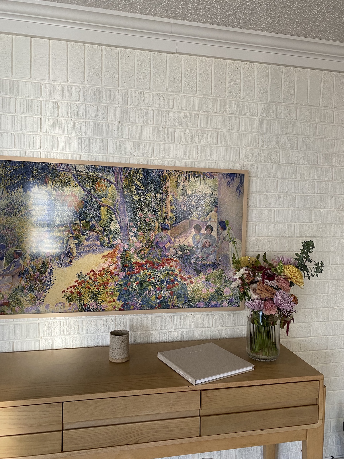 A bright and colorful framed piece of art above a table.