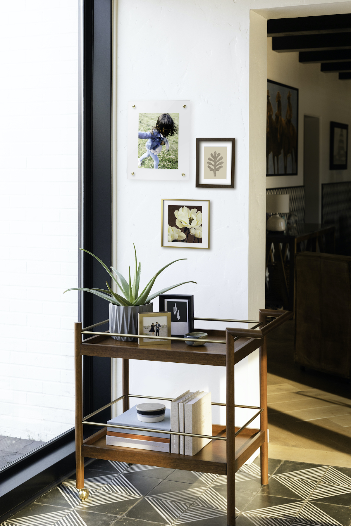 A corner filled with frames, a side table, photo books, and greenery.