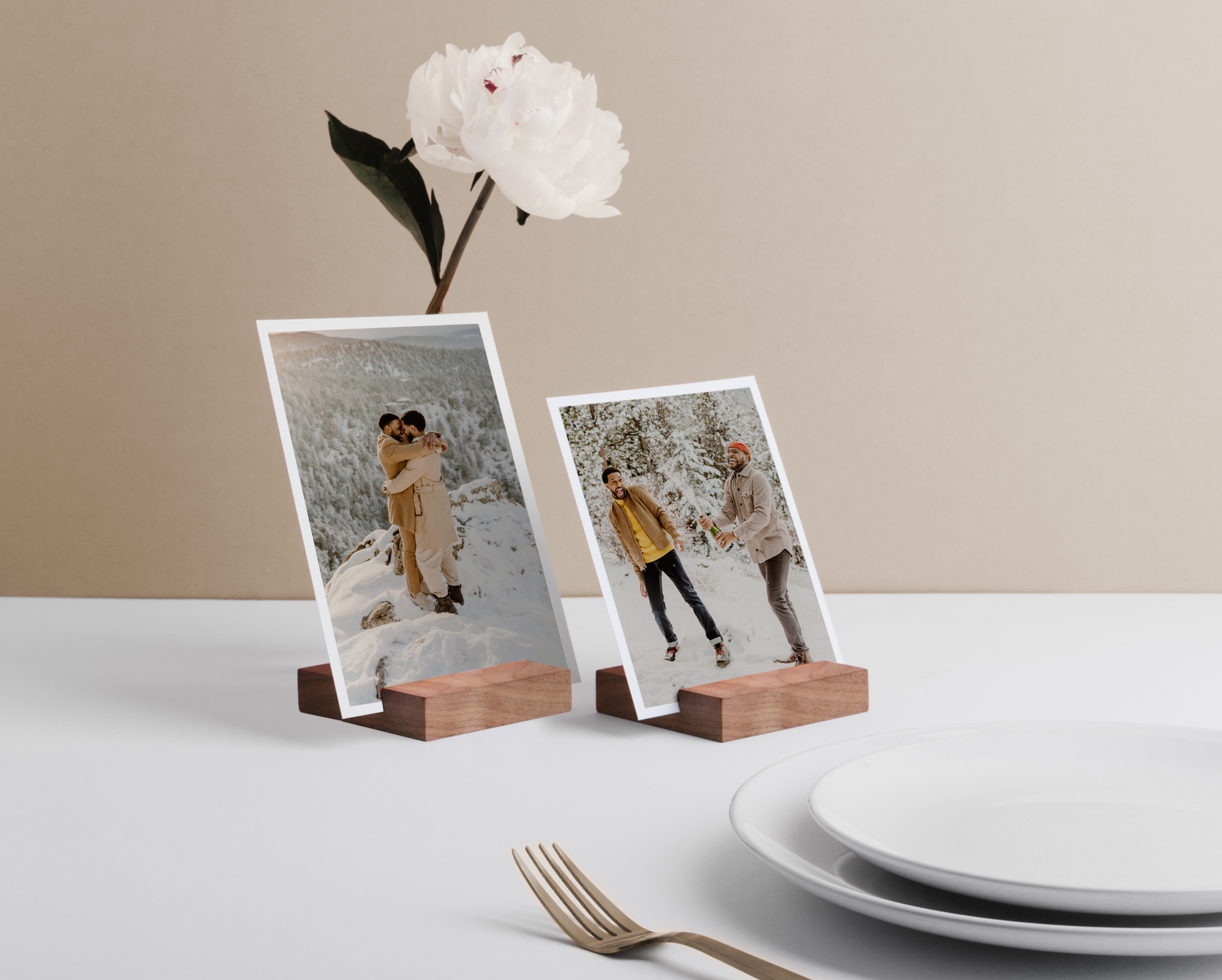 Artifact Uprising Everyday Prints featuring engagement photos of two young men displayed on Walnut Print Blocks beside a wedding place setting