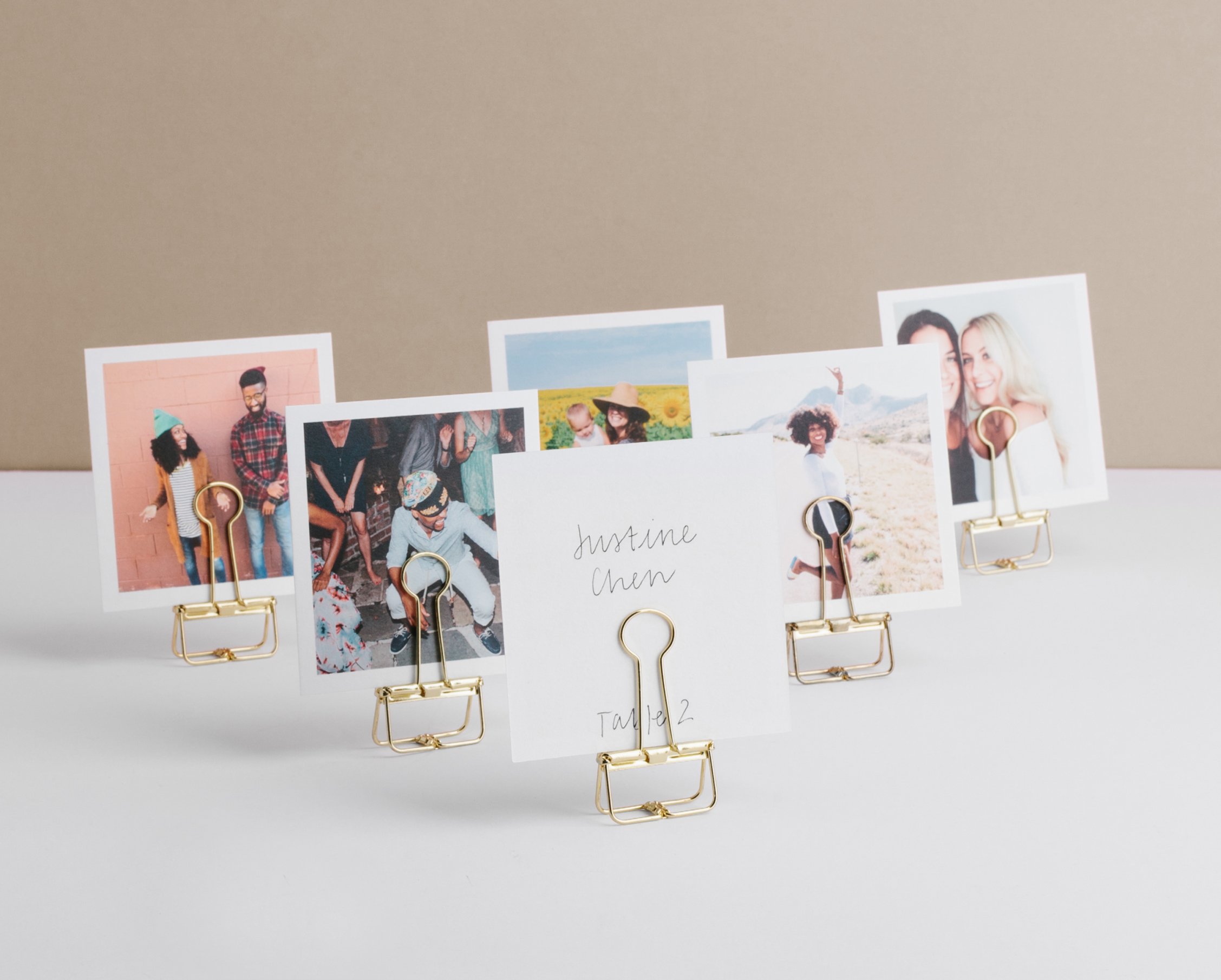 Photos of friends and family featured on Artifact Uprising Square Prints which are displayed on gold binder clips