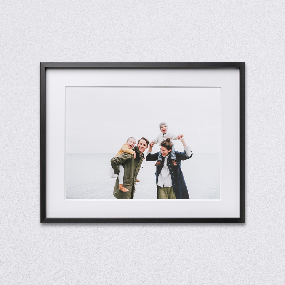 20 x 16 inch Black Modern Metal Frame featuring photo of parents giving two small children piggy back rides on the beach matted to 17 x 13 inch