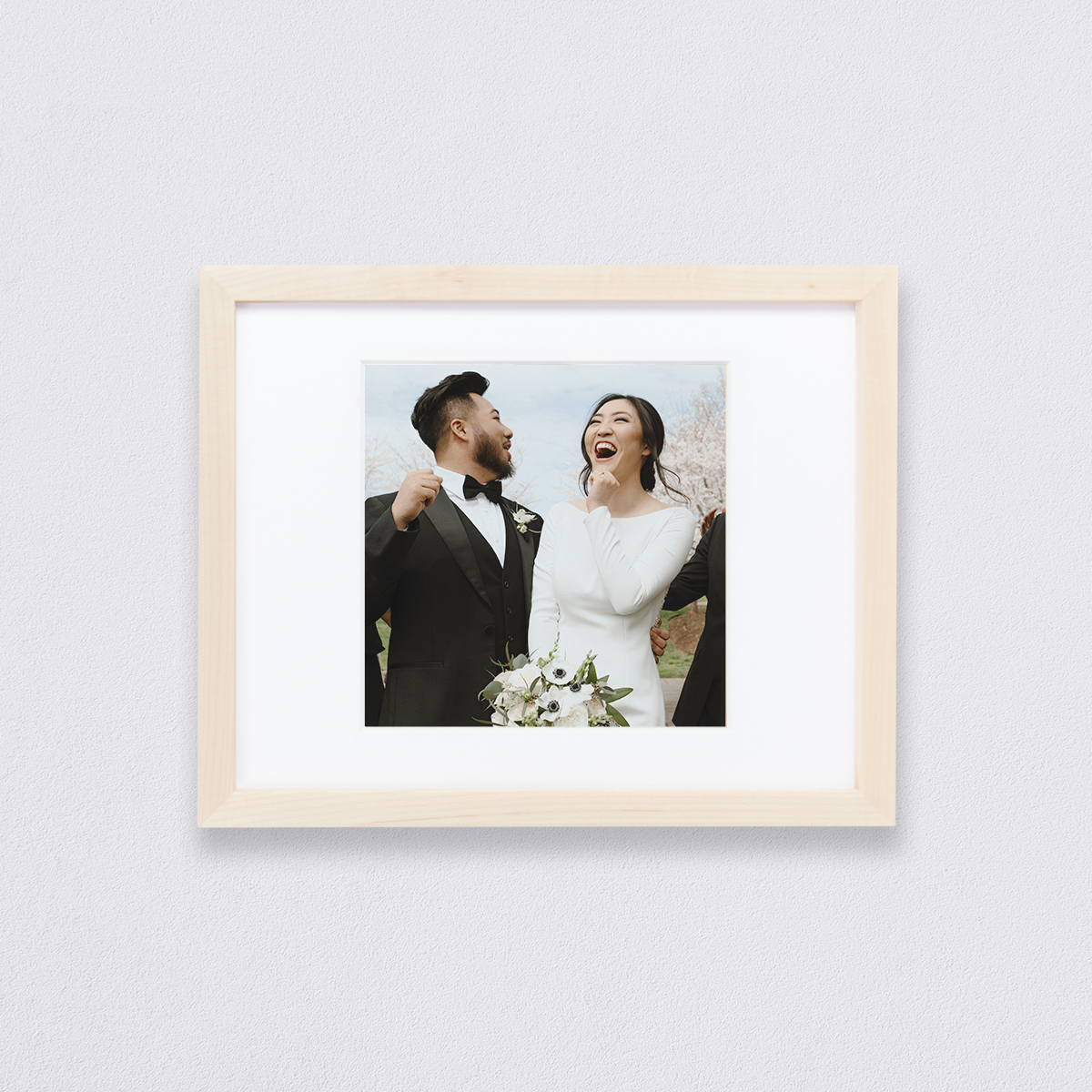 Wedding photo of jubilant couple matted to a 12 inch square inside a maple 20 x 16 inch Artifact Uprising Gallery Frame