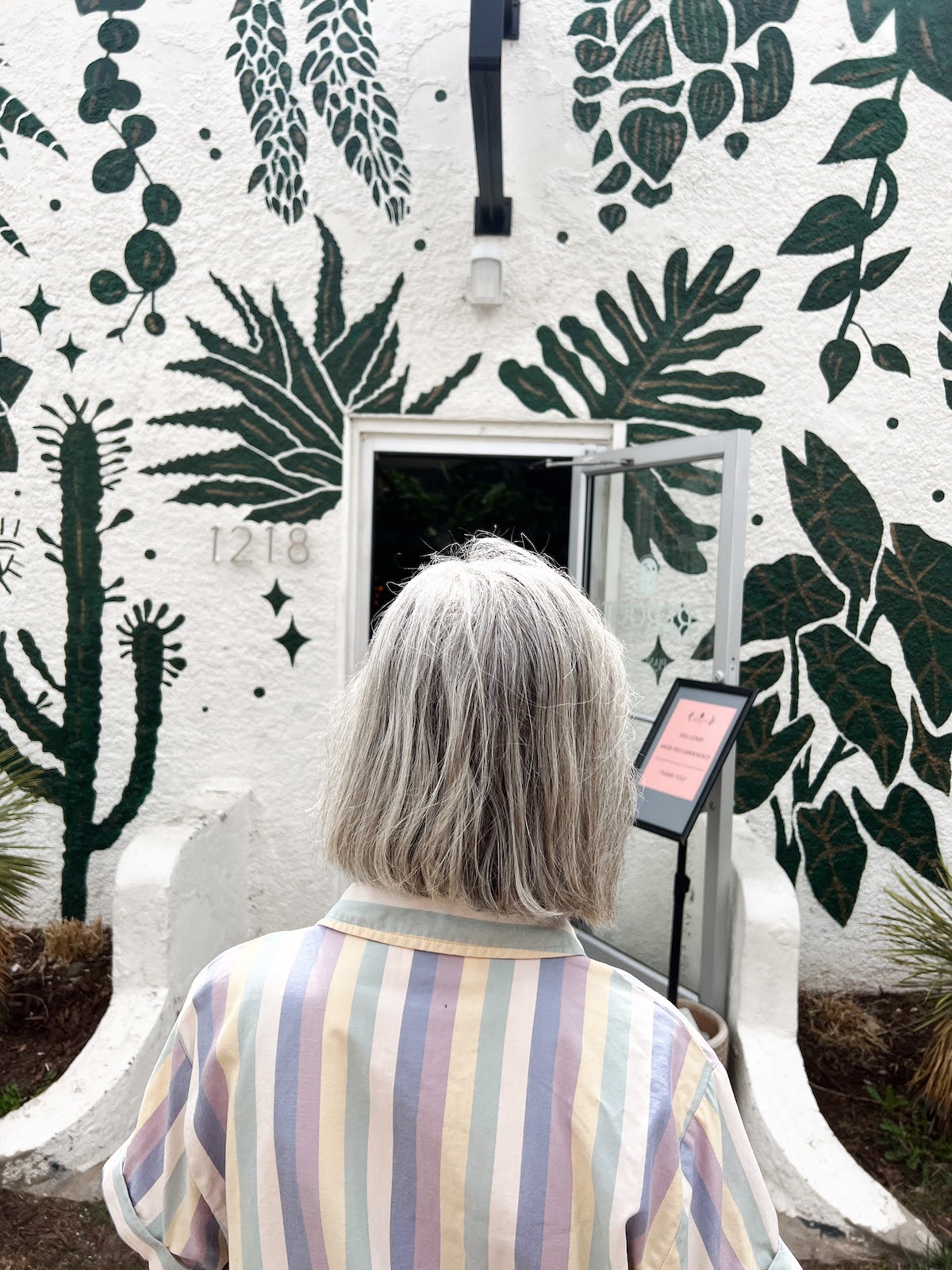 Photo taken from behind of woman looking at art in a gallery