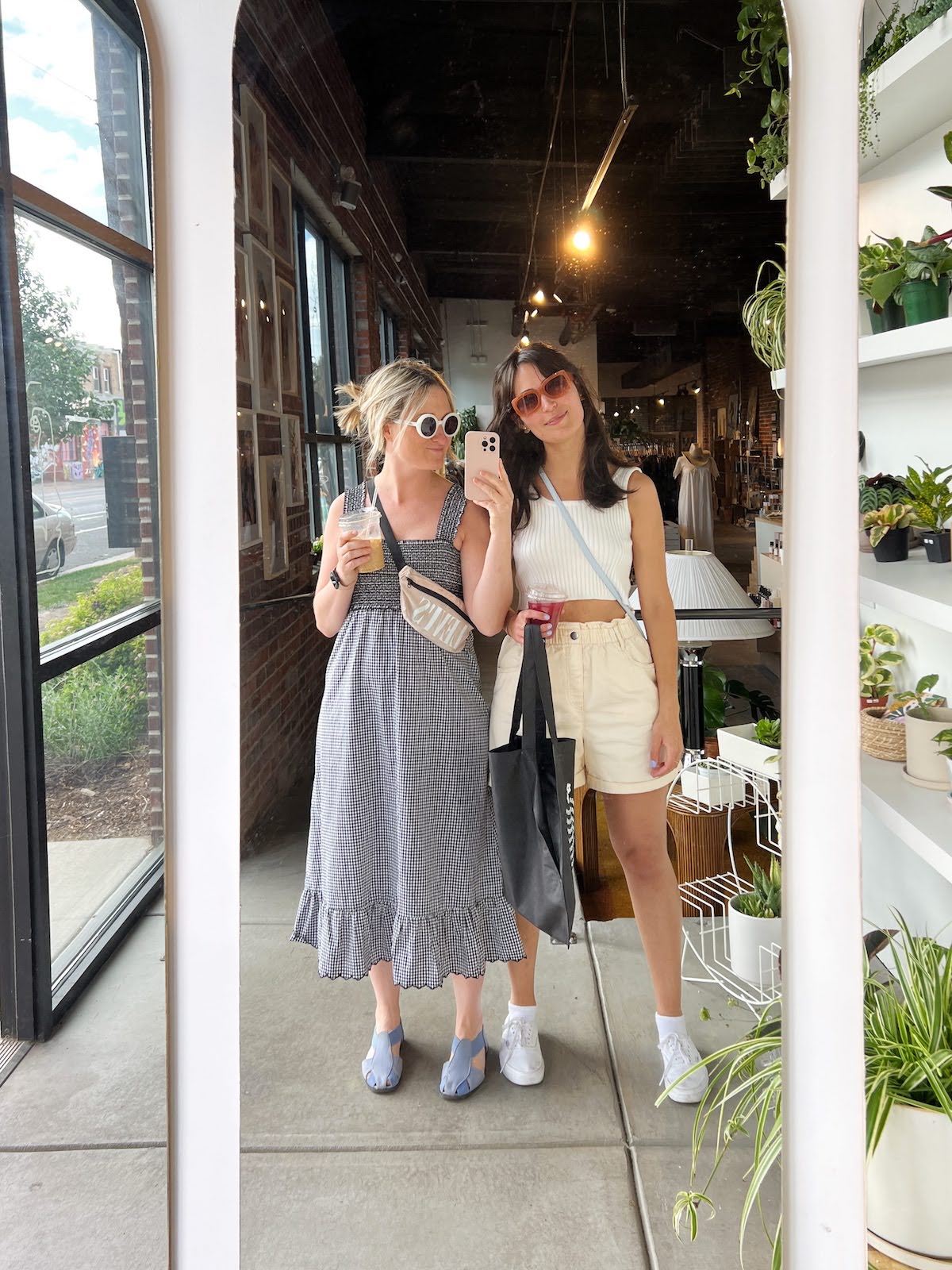 two friends take a selfie in the mirror of a boutique