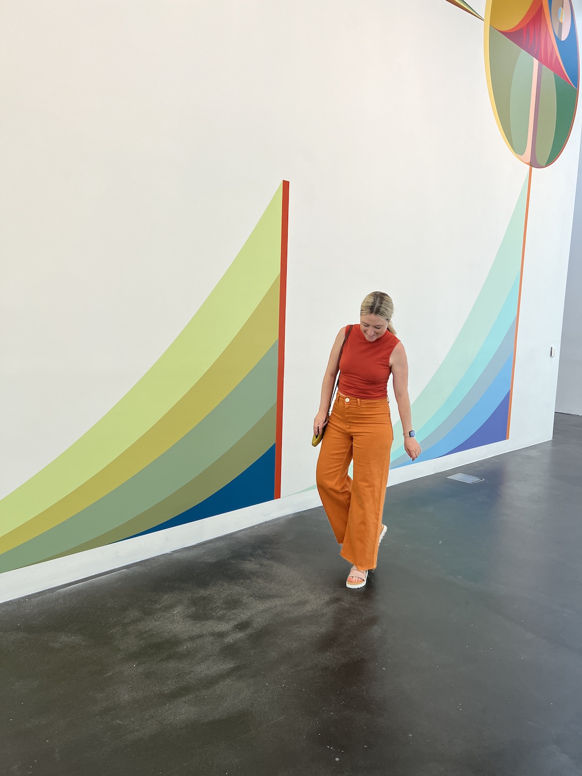 woman walking in front of art pieces with an outfit that matches the bright colors