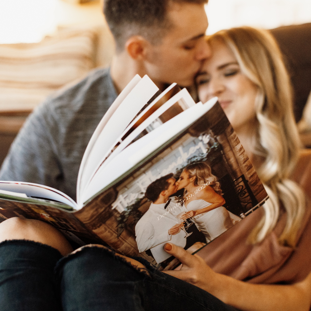 Couple laughing as they look through their wedding album while seated on the floor