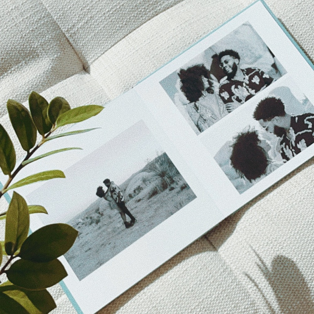 Artifact Uprising Layflat Wedding Photo Album lying open on a couch featuring black and white photos of couple in desert setting